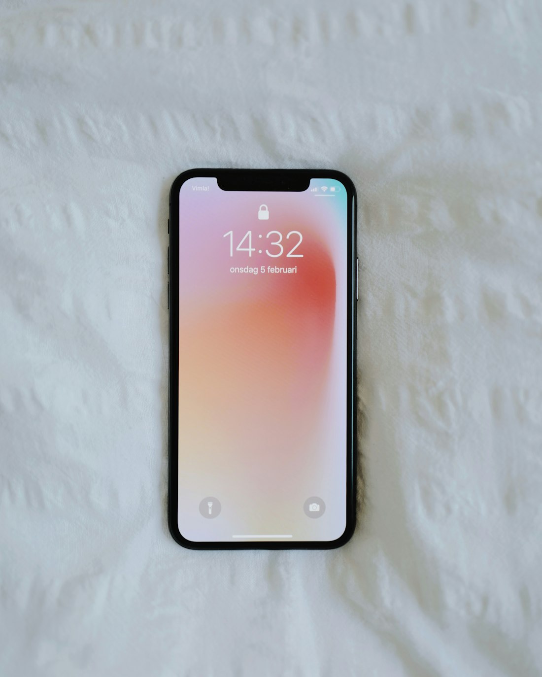 Celular con pantalla de bloqueo sobre una superficie blanca