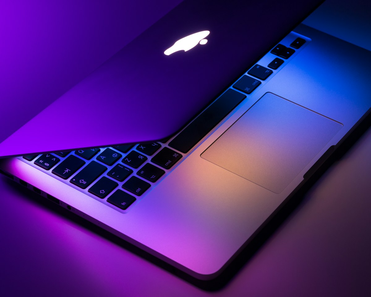 Laptop abierta con teclado retroiluminado en tonos morados